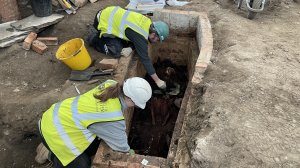 Archaeologists excavate a brick-lined burial vault. 
The brass nameplate read 'John Slater, died 
29th March 1837, aged 77 years'. Image: ULAS.